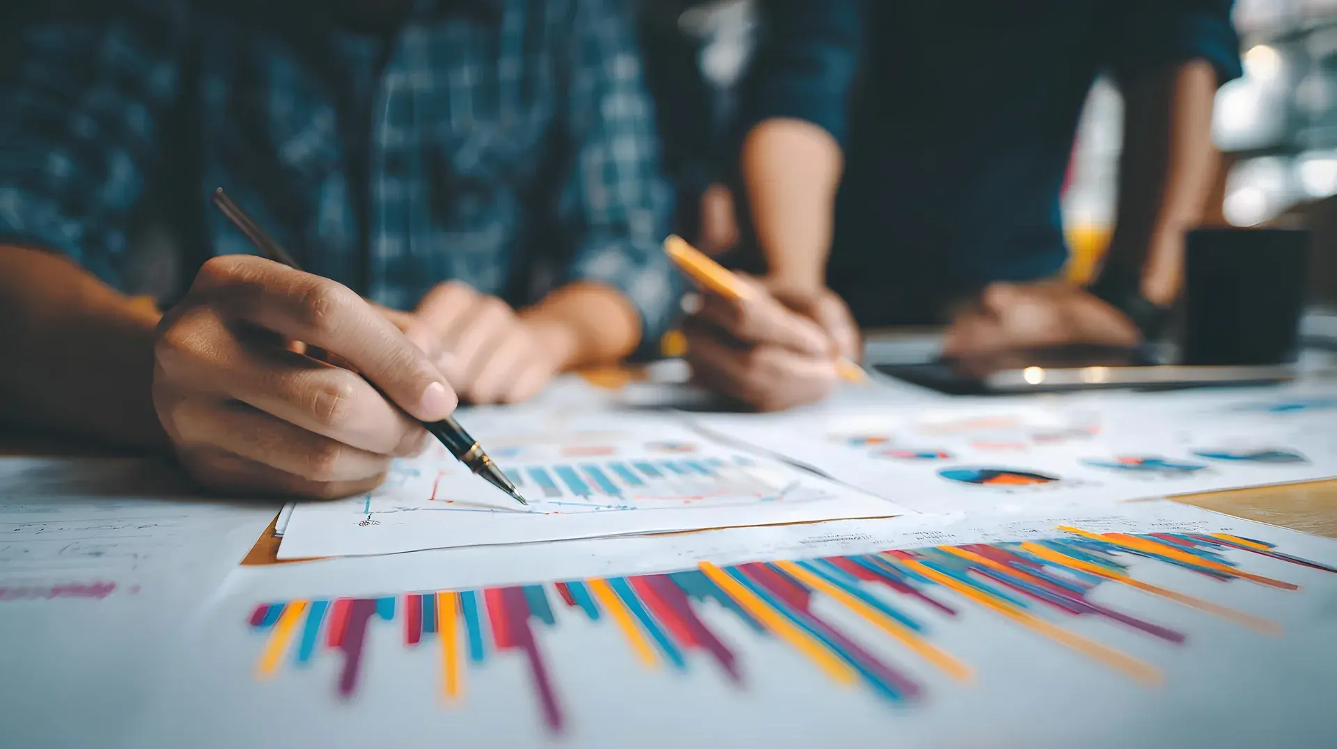 Hands annotating a printed bar chart with a pen during a working session