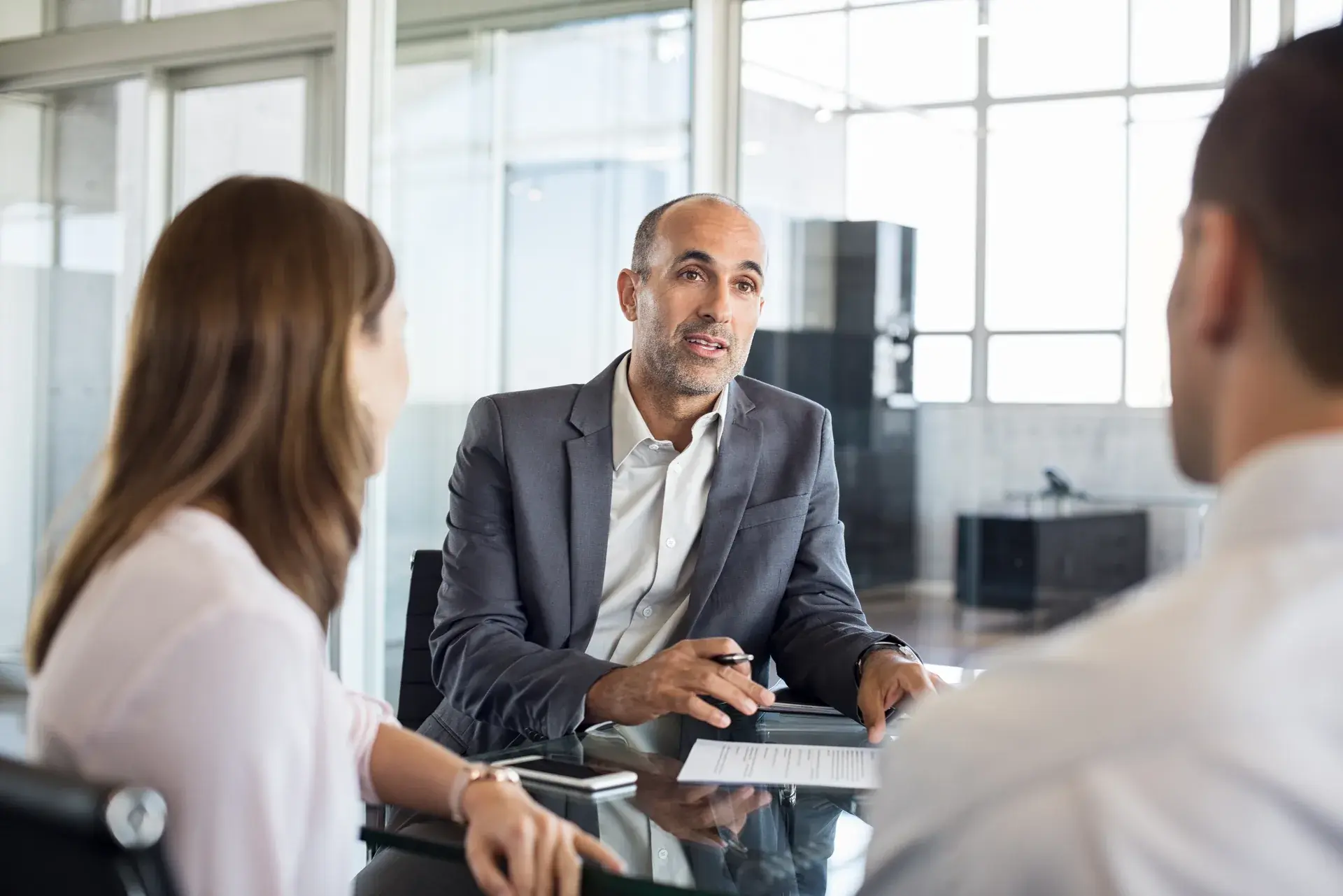 A man leading a discussion with two colleagues in a meeting room