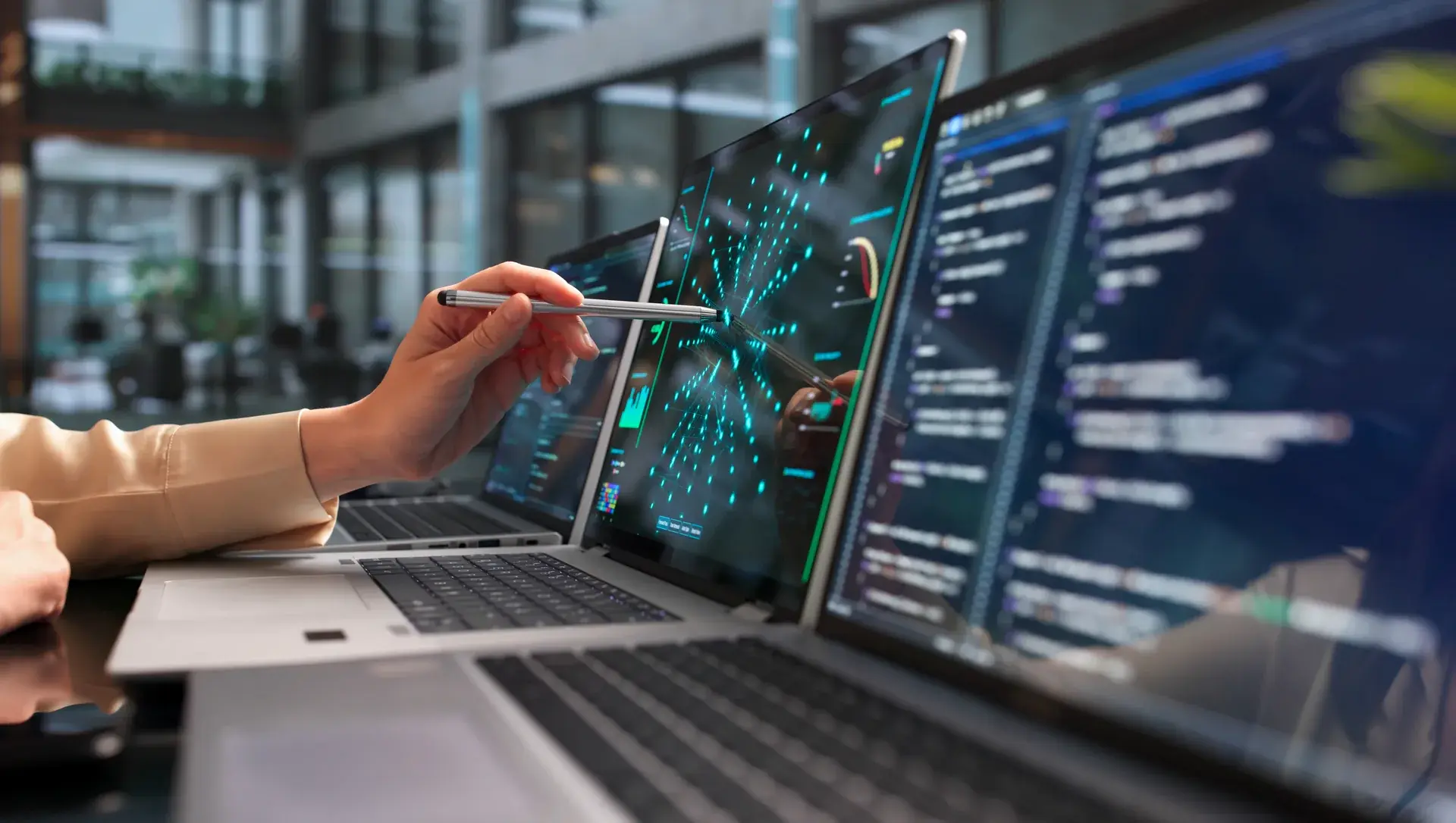 A hand pointing a stylus at a data network visualisation on a laptop screen