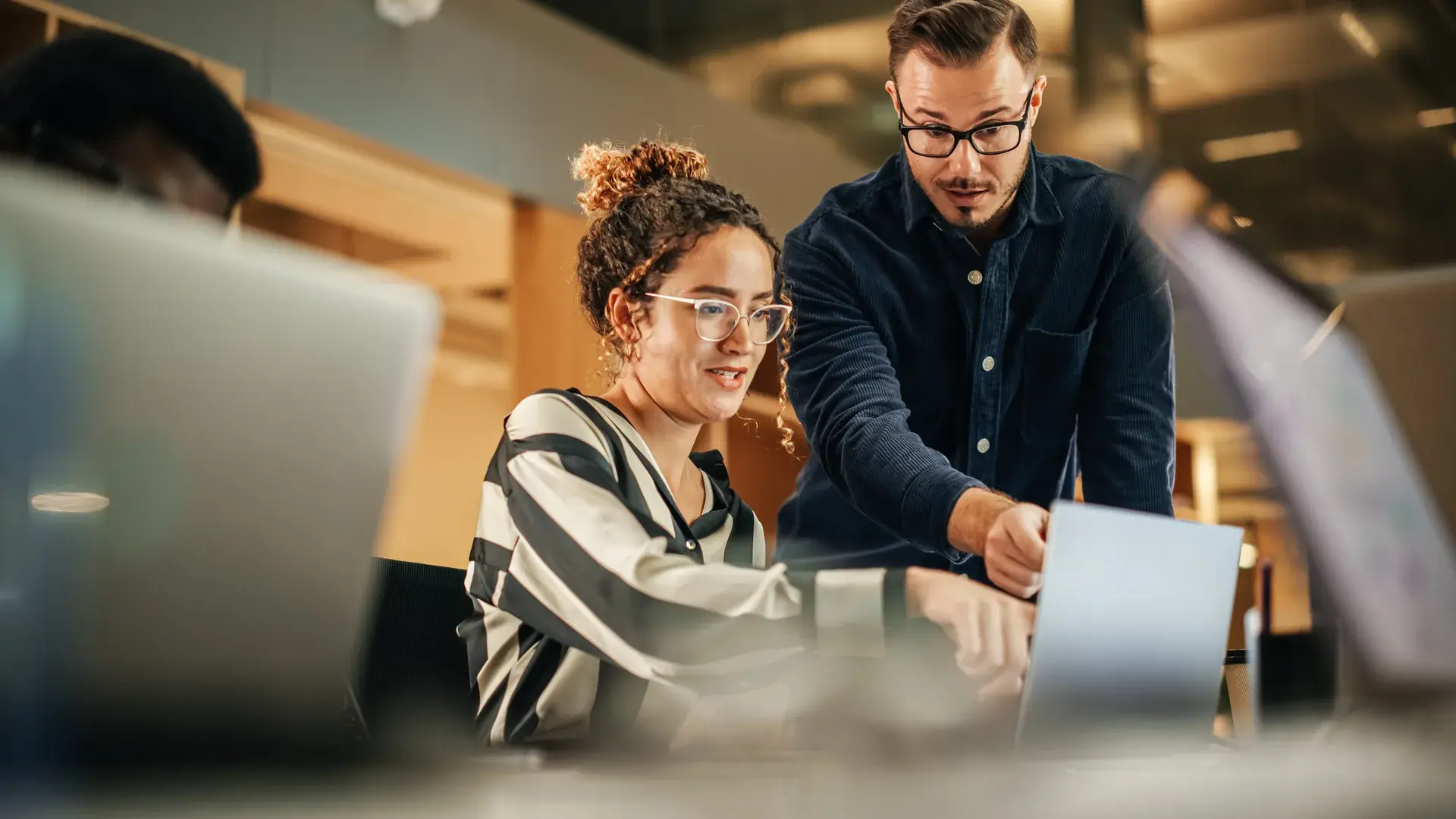 Two analysts reviewing customer data on a monitor in an open office