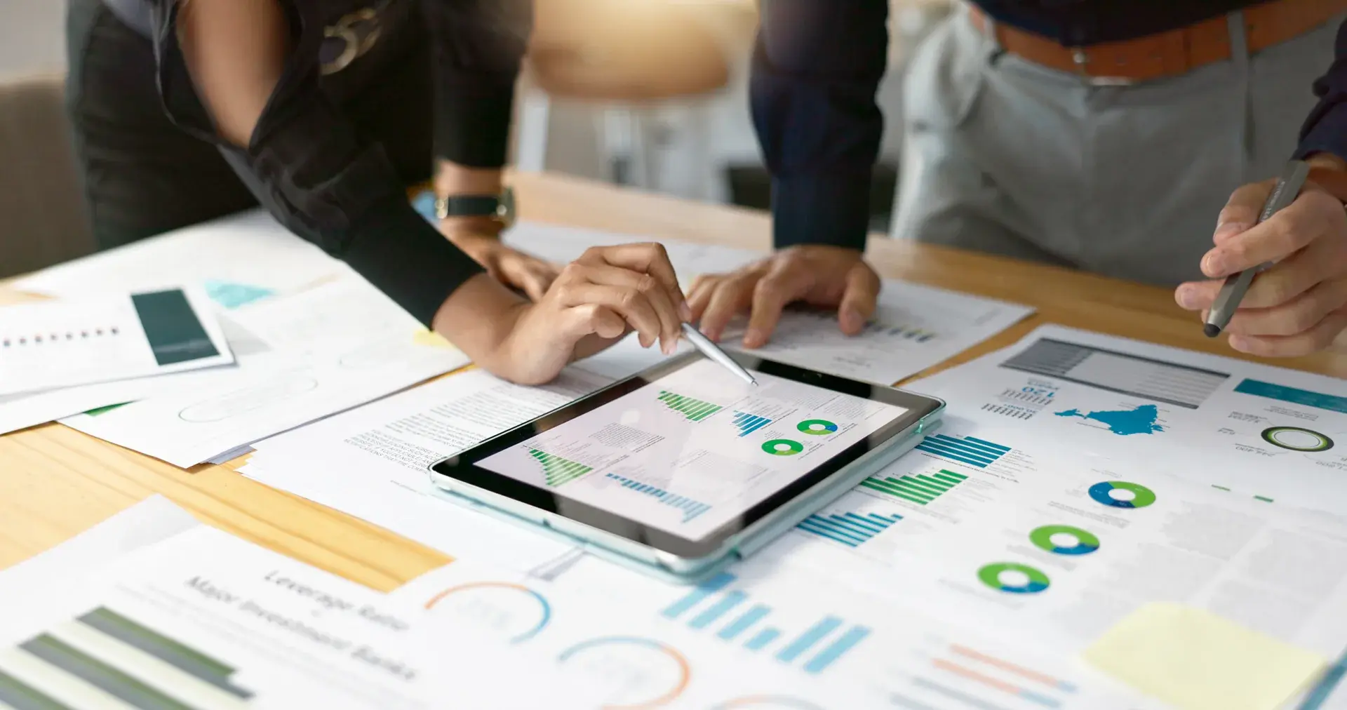 A team reviewing printed charts and a tablet dashboard around a table