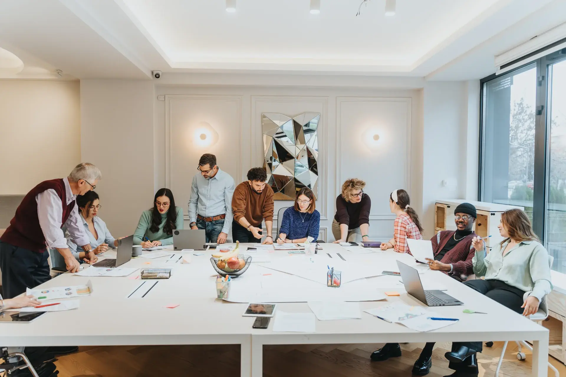Large team collaborating around a table covered in design materials during a brand experience workshop