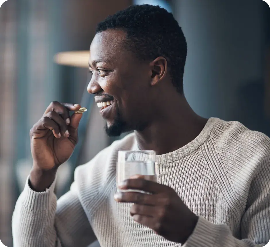A man taking a supplement with a glass of water